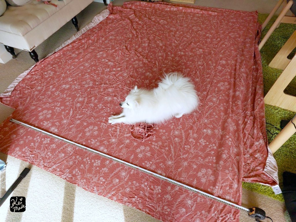 Japanese Spitz dog having a stretch on a bed sheet